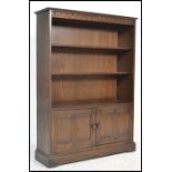 A 20th Century Ercol elm open bookcase, the bookcase having two adjustable shelves over to