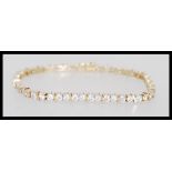 A hallmarked 9ct gold tennis bracelet having a hidden clasp with fold over latch. Set with twin