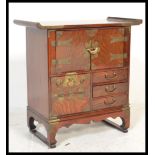 A Chinese table top elm side cabinet of altar shape raised on bracket base with brass bound sides,