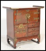 A Chinese table top elm side cabinet of altar shape raised on bracket base with brass bound sides,