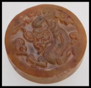 A Chinese Jade roundel seal of mottled brown colour carved with scrolling dragon motif and geometric