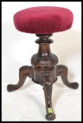 A 19th century Victorian mahogany revolving piano stool raised on splayed legs with carved column