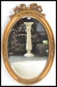 A 20th Century French Rococo style mirror of oval form having beveled glass and a gilt frame with