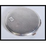 A vintage early 20th Century hallmarked silver compact of circular form having engine turned