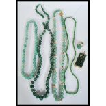 A collection of green stone jade type necklaces along with a green stone and gilt Chinese pendant,