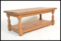 An antique style country pine low coffee table raised on block and turned supports with lower