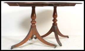 A 20th Century mahogany regency revival twin pedestal D-end dining table raised on baluster