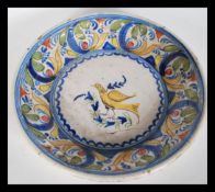 An 18th Century Delft polychrome charger plate depicting a bird to centre with scrolled floral