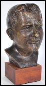 A contemporary desk top bronze bust of a young man raised on a square wooden plinth base. Signed