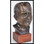 A contemporary desk top bronze bust of a young man raised on a square wooden plinth base. Signed