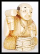 A 19th Century Japanese Meiji period carved ivory netsuke depicting a man working a barrel. Signed