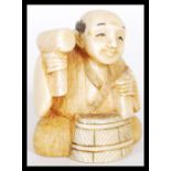 A 19th Century Japanese Meiji period carved ivory netsuke depicting a man working a barrel. Signed