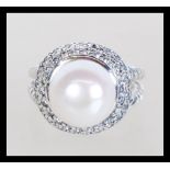 A sterling silver dress ring having a central freshwater pearl and a double halo of CZ stones set