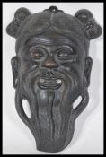 A Japanese cast metal miniature noh mask in the form of a smiling bearded man with a pierced mouth