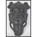 A Japanese cast metal miniature noh mask in the form of a smiling bearded man with a pierced mouth