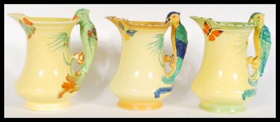 A set of three of early 20th Century Burleigh Ware Art Deco water jugs, the handles modelled as