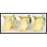 A set of three of early 20th Century Burleigh Ware Art Deco water jugs, the handles modelled as