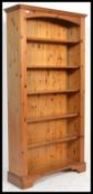 An antique style country pine large tall bookcase cabinet raised on bracket feet with a set of