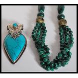 A beaded malachite necklace with bronzed tribal beads along with a silver pendant having a pear