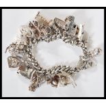 A 20th Century vintage silver hallmarked charm bracelet having a curb linked chain with nineteen