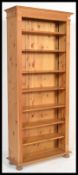 An antique style country pine large tall bookcase cabinet raised on bun feet with a set of seven