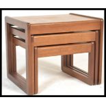 A retro 20th Century Danish inspired teak wood nest of three graduating tables, square tops raised