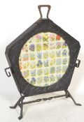An unusual late 19th / early 20th Century cast iron fire screen of pentagonal shape with embroidered