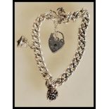 A silver hallmarked curb link bracelet having a heart lock and safety chain with two charms to