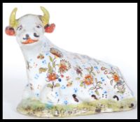 A 19th Century Delft Faience Staffordshire type figurine in the form of a seated reclined cow with