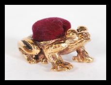 A vintage style copper pincushion in the form of a frog having red baize pin cushion to top.