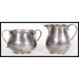 A silver hallmarked creamer jug having a scrolled handle with reeded decoration to the neck and a