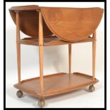 An Ercol beech and elm blonde three tier buffet trolley having three gallery surround trays with