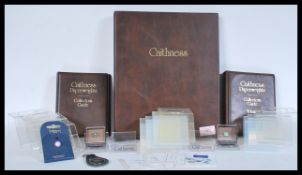 A collection of Caithness collectors items to include stands, binders, keychain, miniature