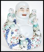 A 20th Century decorative ceramic figure of the laughing Buddha, depicted seated with clambering