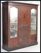 An Edwardian mahogany triple wardrobe, the shaped pediment over a central panelled door above four