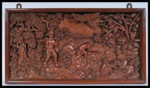 An early 20th century large carved wooden plaque depicting men at work amongst trees with children