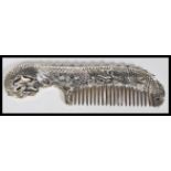 A Chinese 20th Century silver plated comb in the form of a dragon having scrolled decoration.