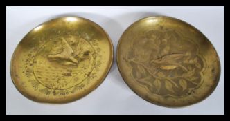 A pair of early 20th Century Arts and Crafts brass wall plaques of circular form depicting birds