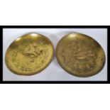 A pair of early 20th Century Arts and Crafts brass wall plaques of circular form depicting birds