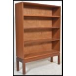 A retro mid century teak wood open bookcase by McIntosh of Kirkcaldy being fitted with three