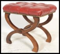 A 20th Century Georgian revival red leather button back padded footstool of Glastonbury form, raised