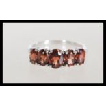A hallmarked 9ct white gold five stone garnet ring having a large central faceted stone flanked by