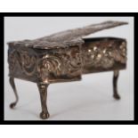 A silver hallmarked miniature doll's house harpsichord having embossed Rococo decoration and an