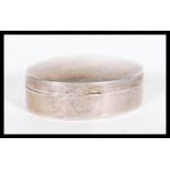 A silver hallmarked pill box by Ari D Norman of oval form having a domed hinged lid. Hallmarked