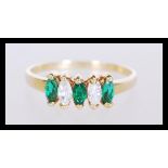 A stamped 18ct gold ring set with three green marquise cut stones and two white marquise cut stones.