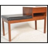 A vintage teak wood telephone table having a telephone book storage area and a black vinyl seat