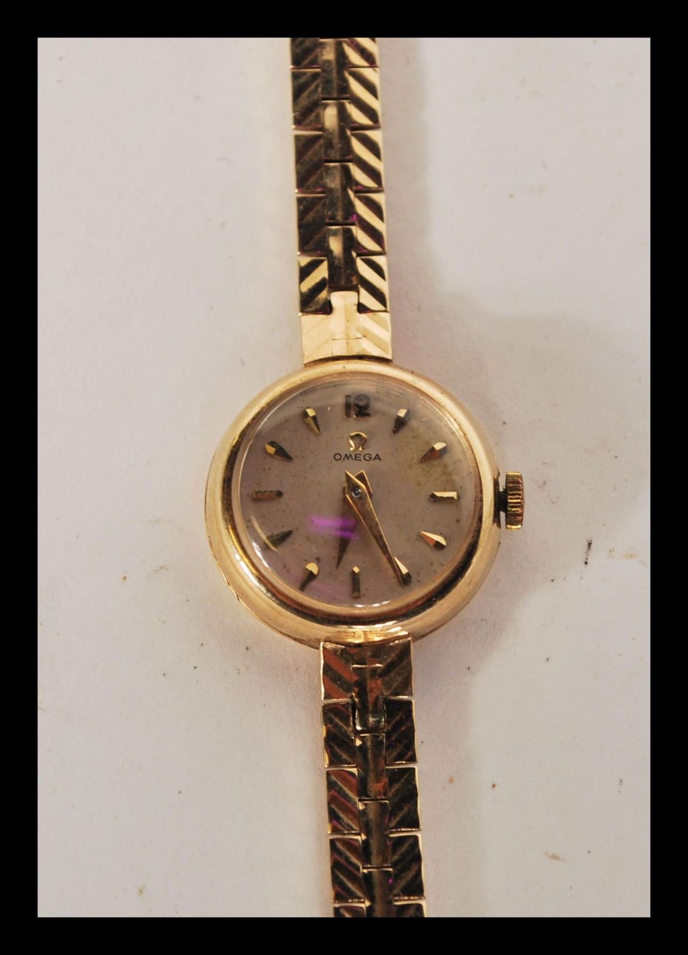 A hallmarked 9ct gold ladies Omega cocktail watch set to a 9ct gold watch bracelet. Champagne dial