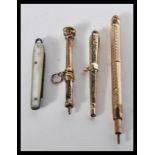 A group of three yellow metal propelling pencils along with a miniature mother of pearl pen fruit