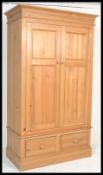 An antique style large country pine double wardrobe. Raised on a plinth base with drawers having a