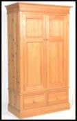 An antique style large country pine double wardrobe. Raised on a plinth base with drawers having a